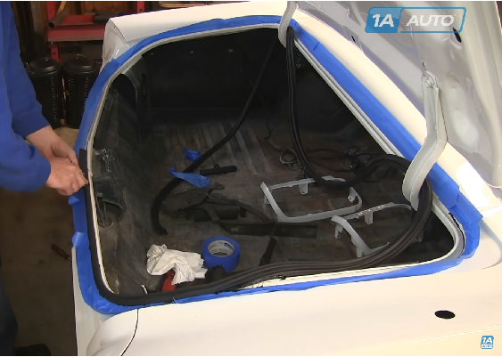 1A Auto mechanic installing weatherstripping around trunk