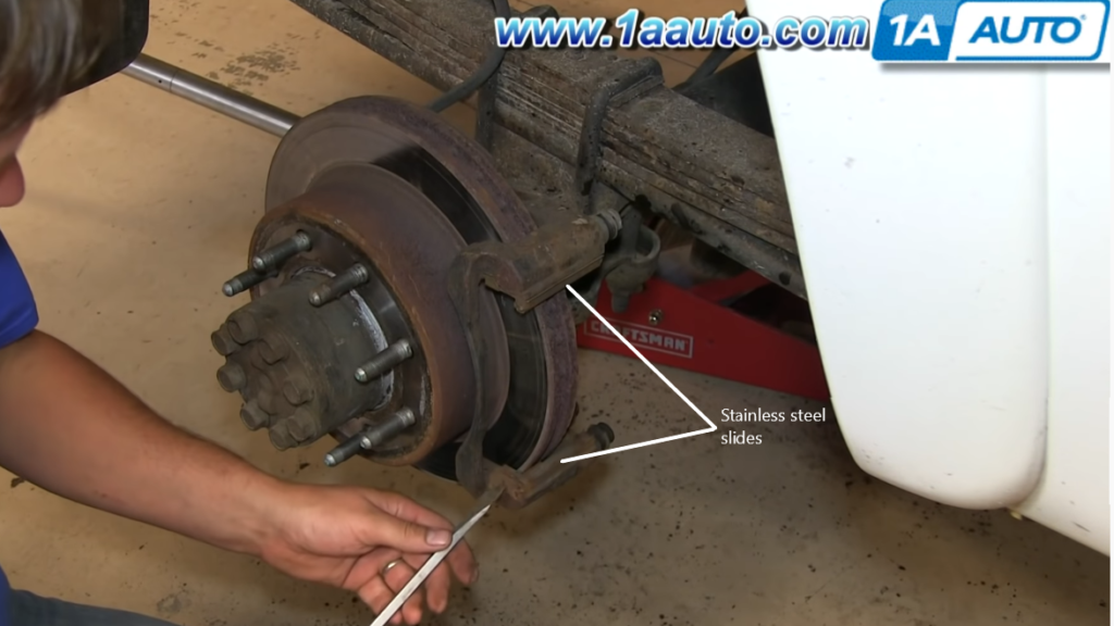 Use a large screwdriver or pry bar to remove the stainless steel slides that hold the brake pads.
