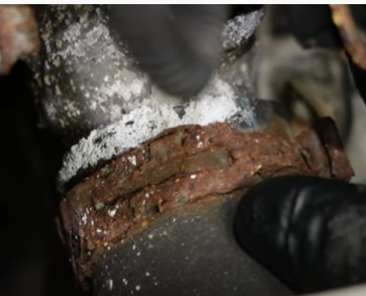 Corroded radiator hose and hose clamp with white deposits