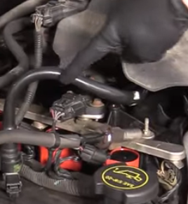 Mechanic pointing to a PCV valve on the 2nd gen Ford Crown Vic