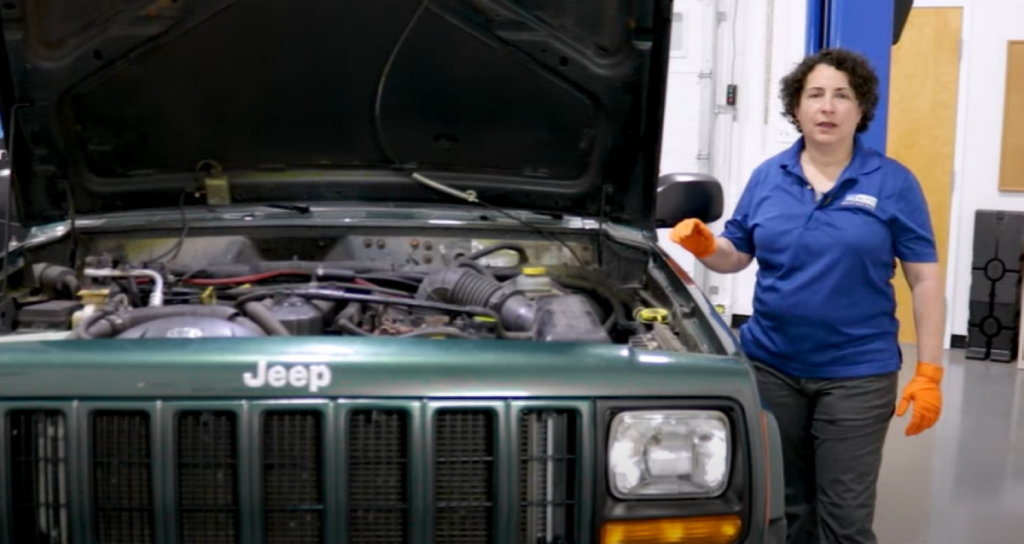 1A Auto mechanic Sue next to the 1984 to 2001 Cherokee and reviewing common 4.0 liter Jeep engine problems