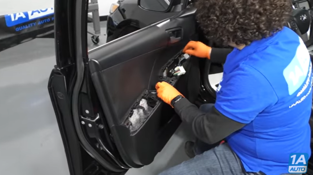 Mechanic installing a door panel after demonstrating how to remove one