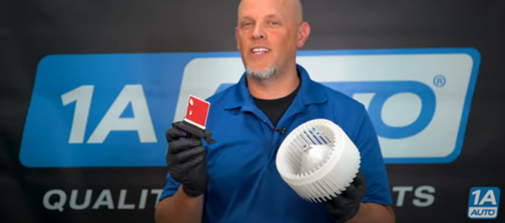 Mechanic holding a blower motor and blower motor resistor reviewing how a car fan can only work on high
