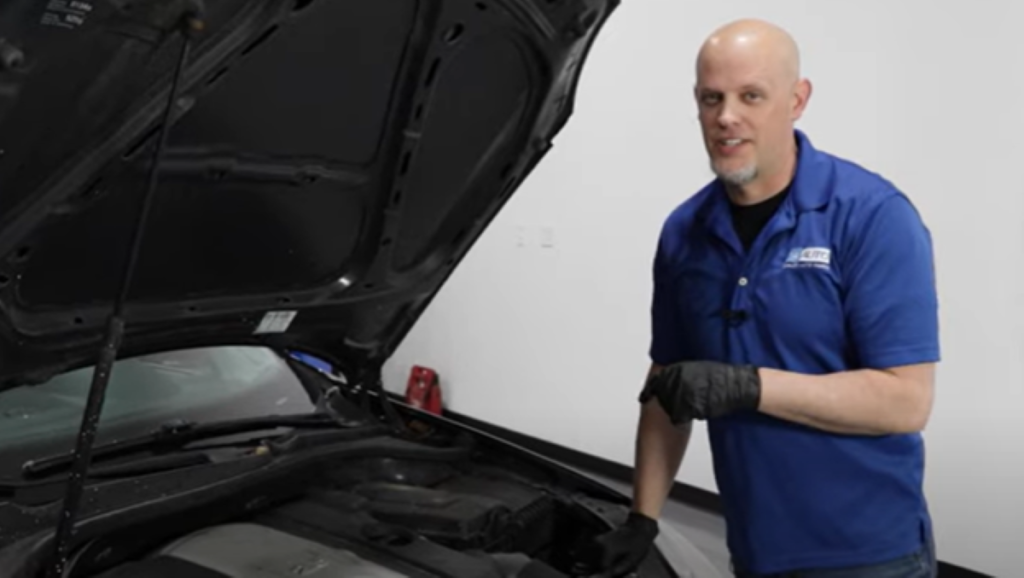 Mechanic standing in front of a 5th generation 2005 to 2010 Volkswagen VW Jetta with the hood open reviewing the top 4 problems with the 2.5 liter engine
