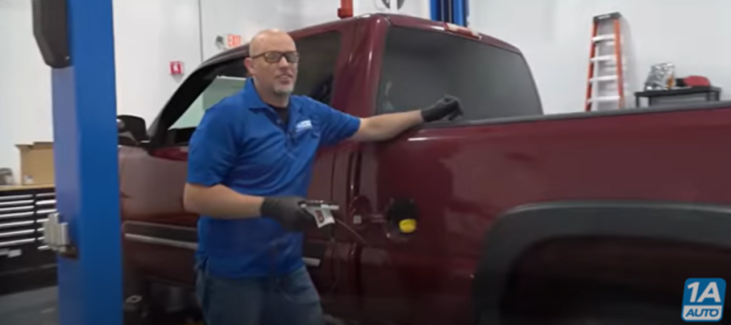 Mechanic standing next to a truck near the gas cap holding a boroscope to test why the gas pump keeps stopping when pumping gas