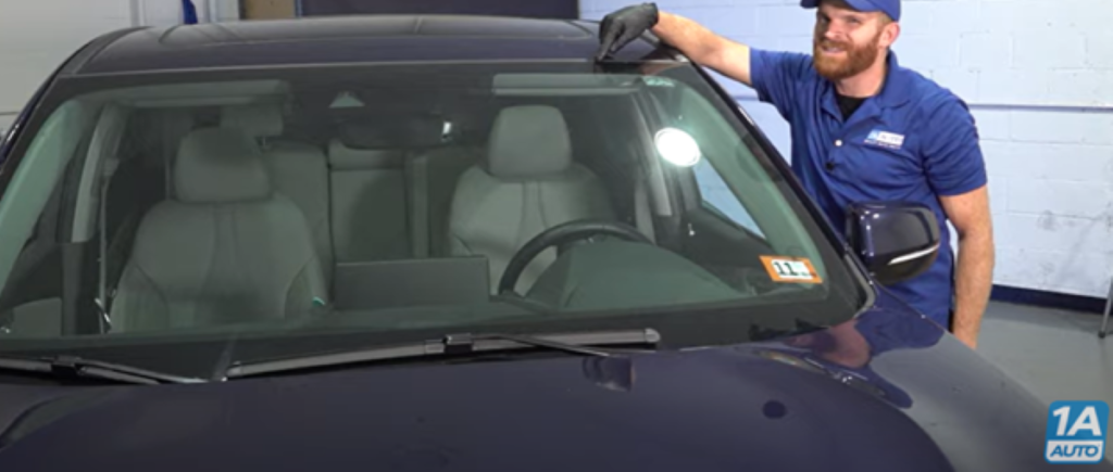 Mechanic pointing to the top of a 2019 to 2021 Acura RDX windshield where popping noises can happen