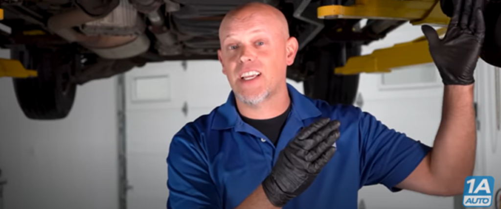 Mechanic under a lifted vehicle reviewing how to diagnose a clunking noise, bad control arm bushing symptoms, and more