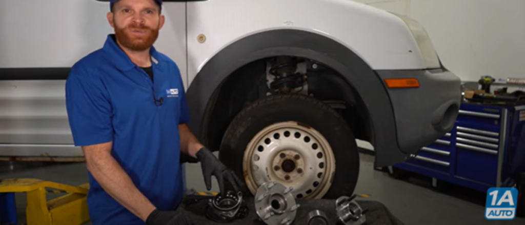 Mechanic standing in front of a truck with wheel bearing hub assemblies on a table