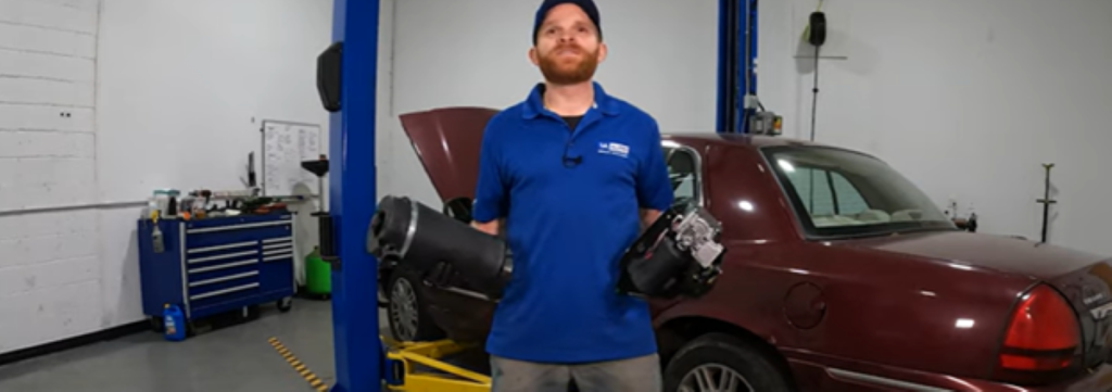 Mechanic holding two air suspension parts, an airbag and compressor