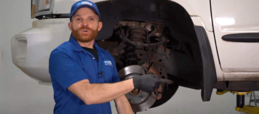Mechanic standing next to a 2005 and 2010 Dodge Dakota reviewing how upper ball joints are one of its top 5 common problems